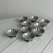 Set of 9 low bowls in shiny stainless steel.