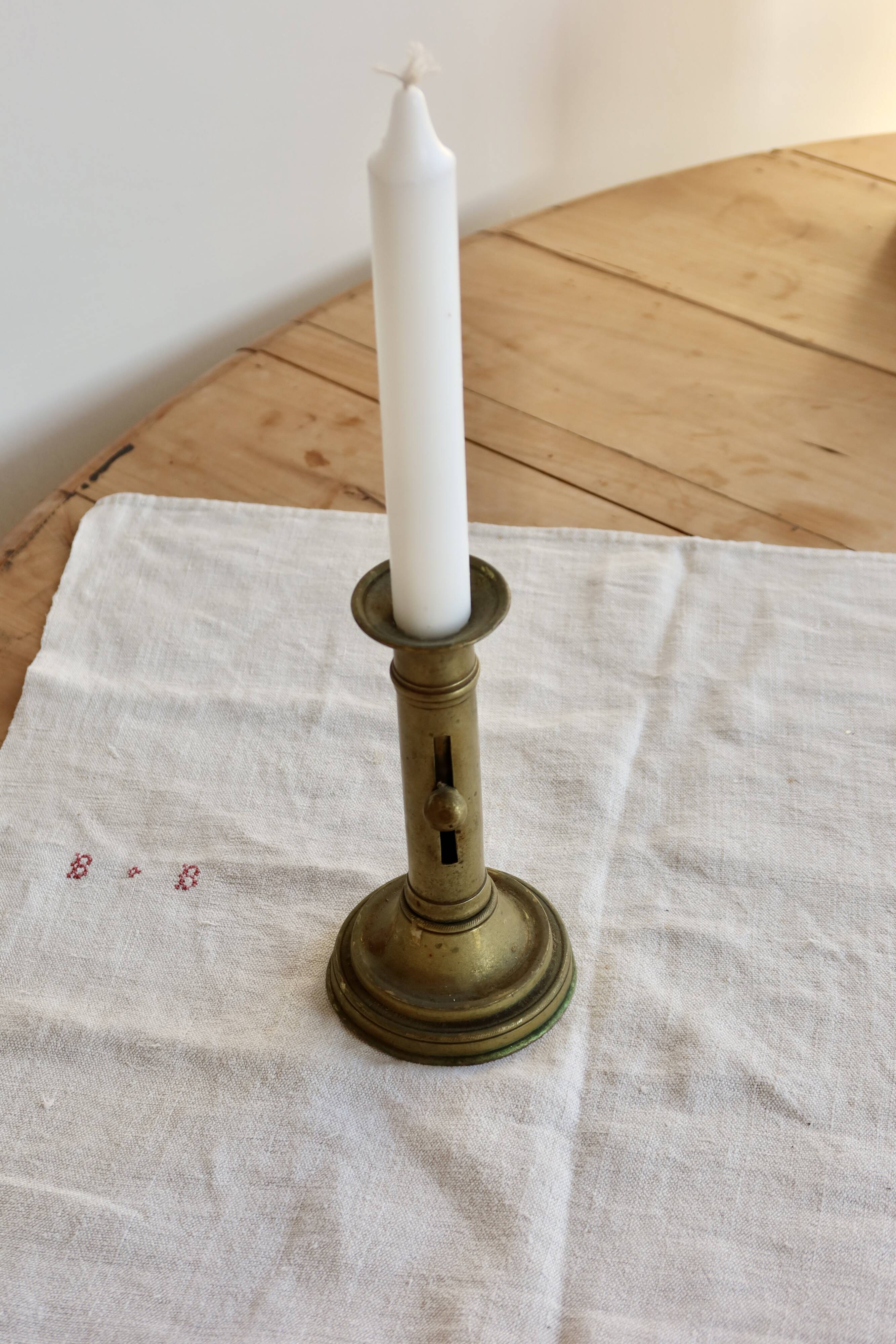 Antique brass candlestick with a push button.