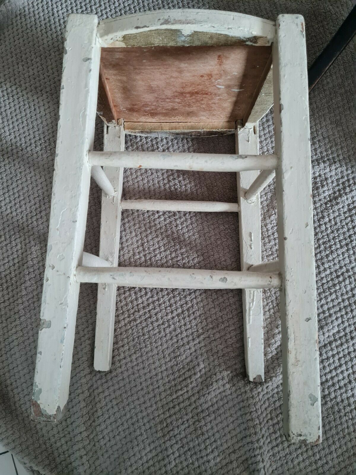 Vintage wooden stool with white peeling paint