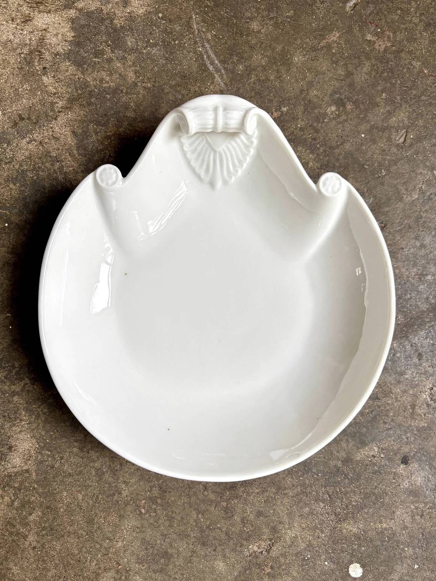 Small, shallow porcelain dish shaped like a seashell