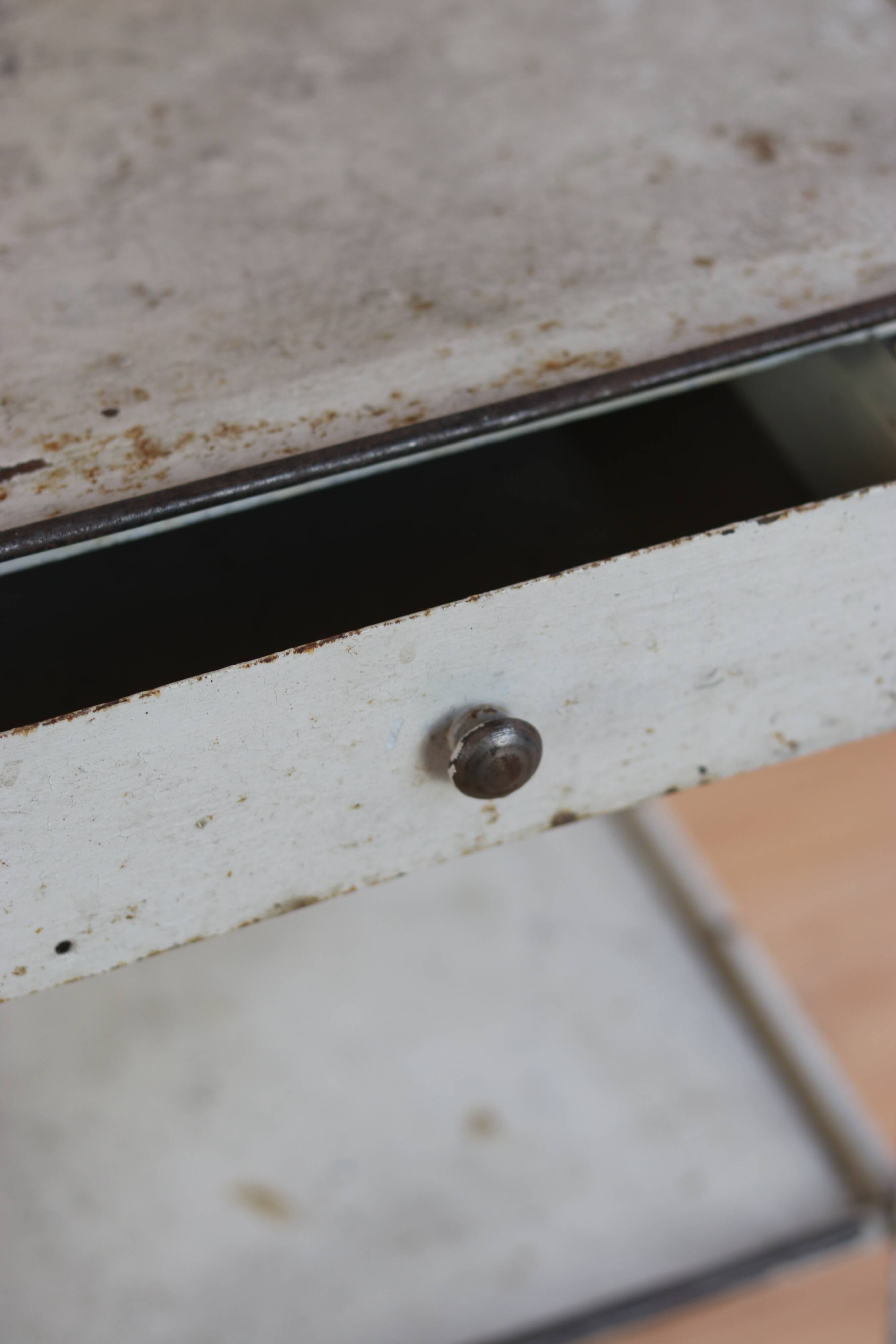 Painted metal side table, patinated white, with a drawer and two shelves