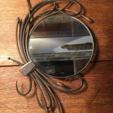 Round mirror surrounded by art deco style metal plants