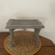 Small footrest bench in solid wood with a slate grey patina.