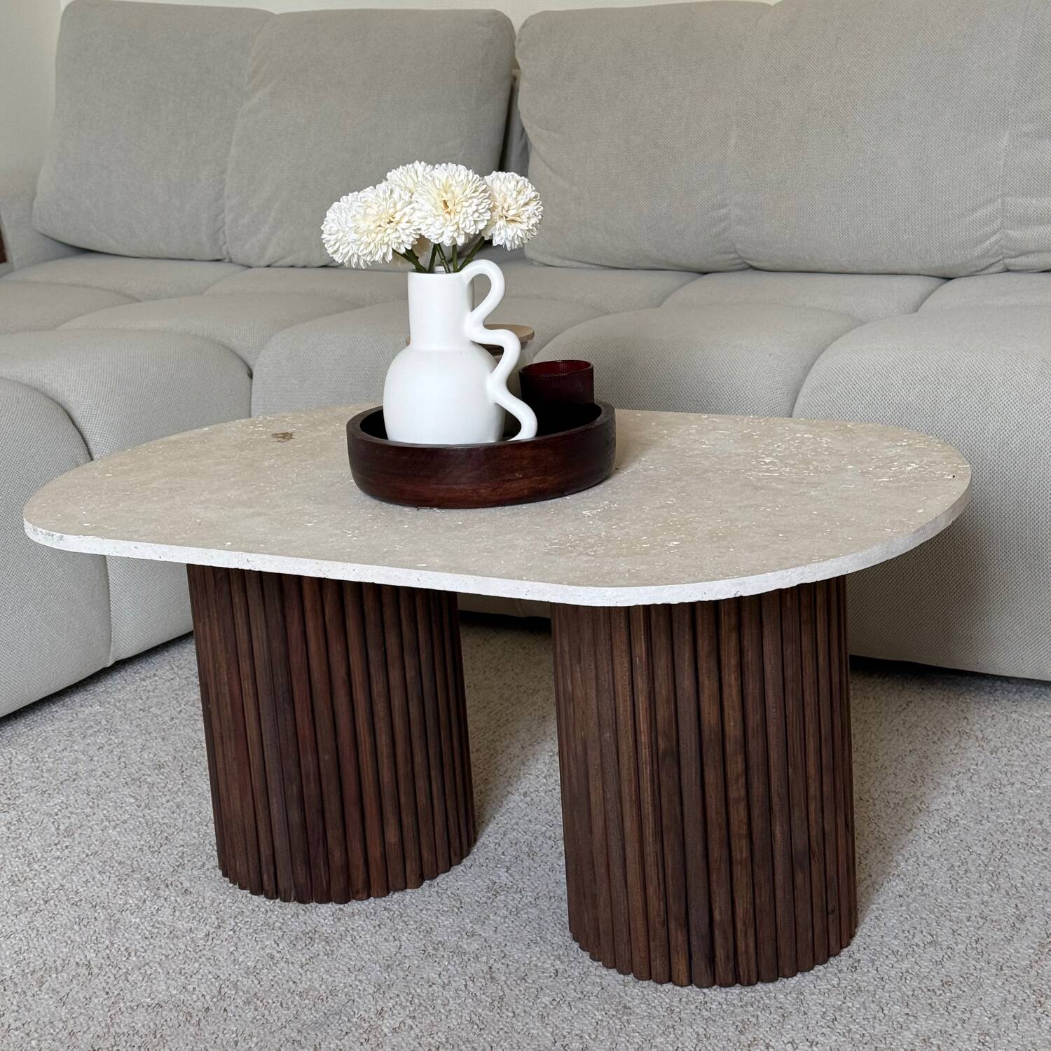 Oval coffee table in travertine and fluted wood.