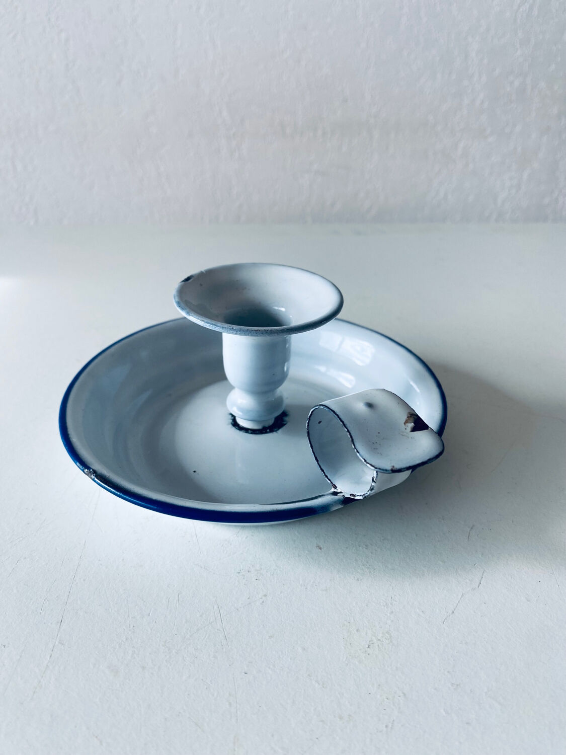 Old candle holder in white enameled metal