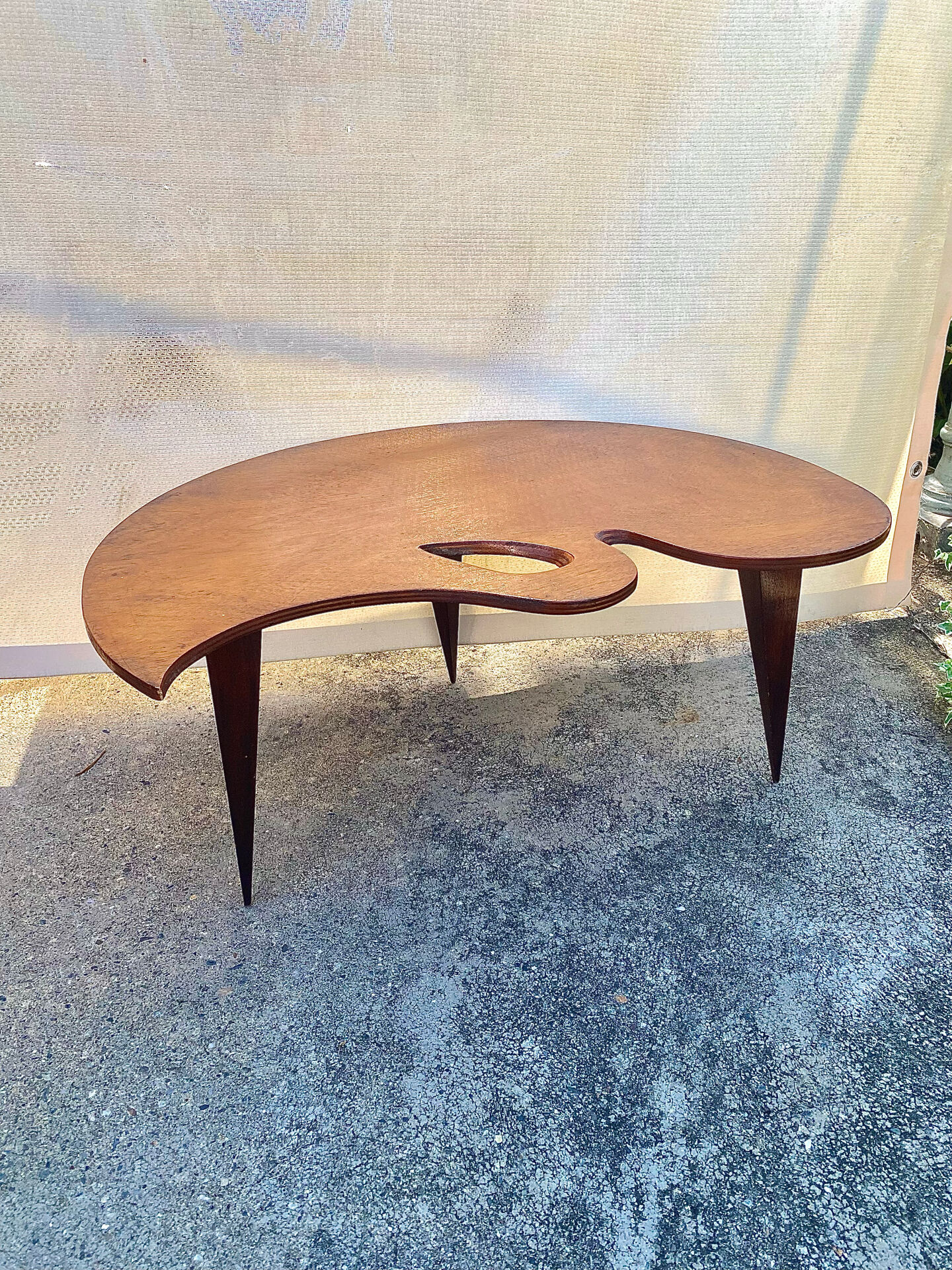 Mid-century coffee table with a palette shape and splayed legs.