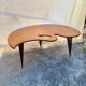 Mid-century coffee table with a palette shape and splayed legs.