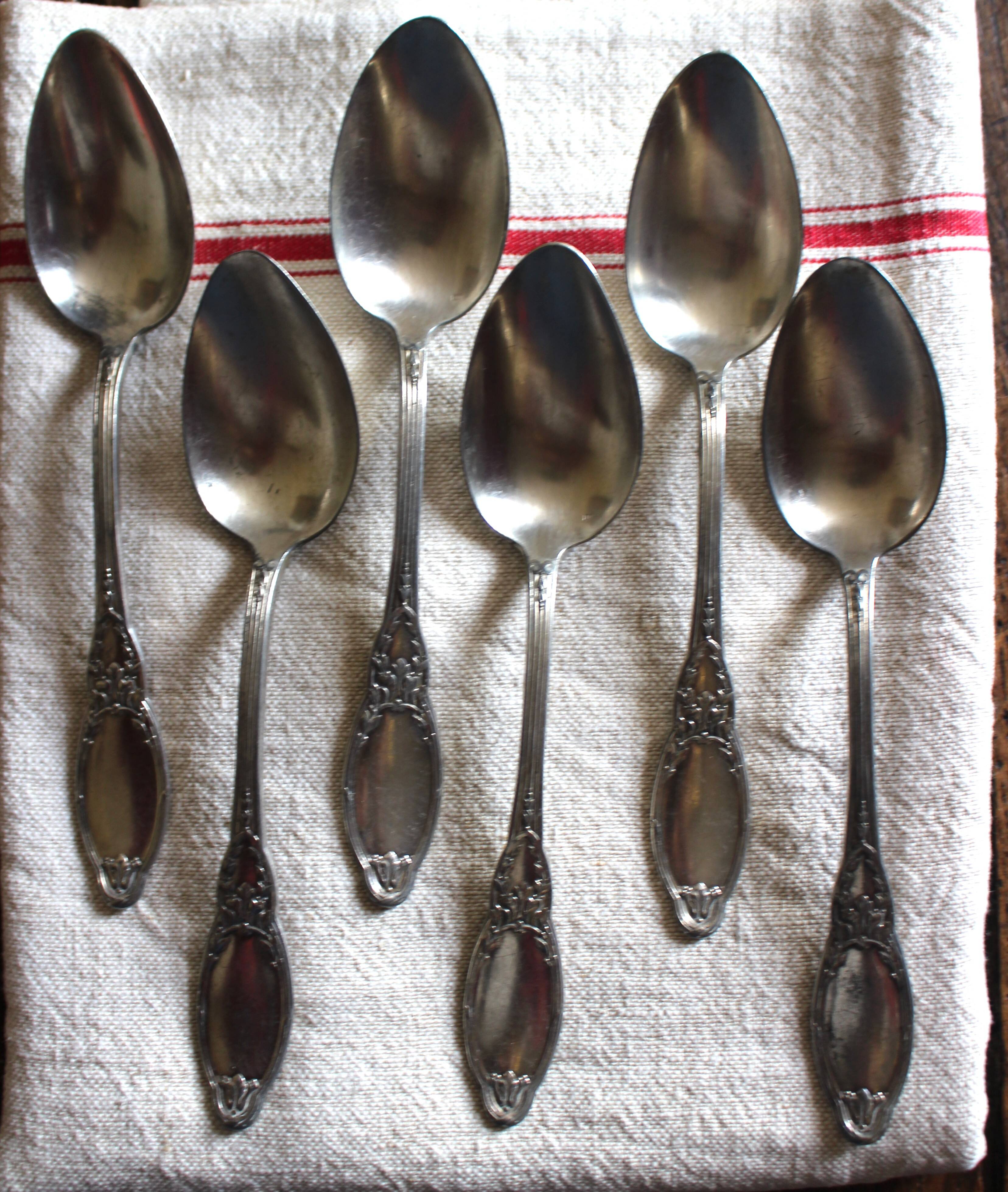 A set of 6 silver-plated metal soup spoons with foliage design.