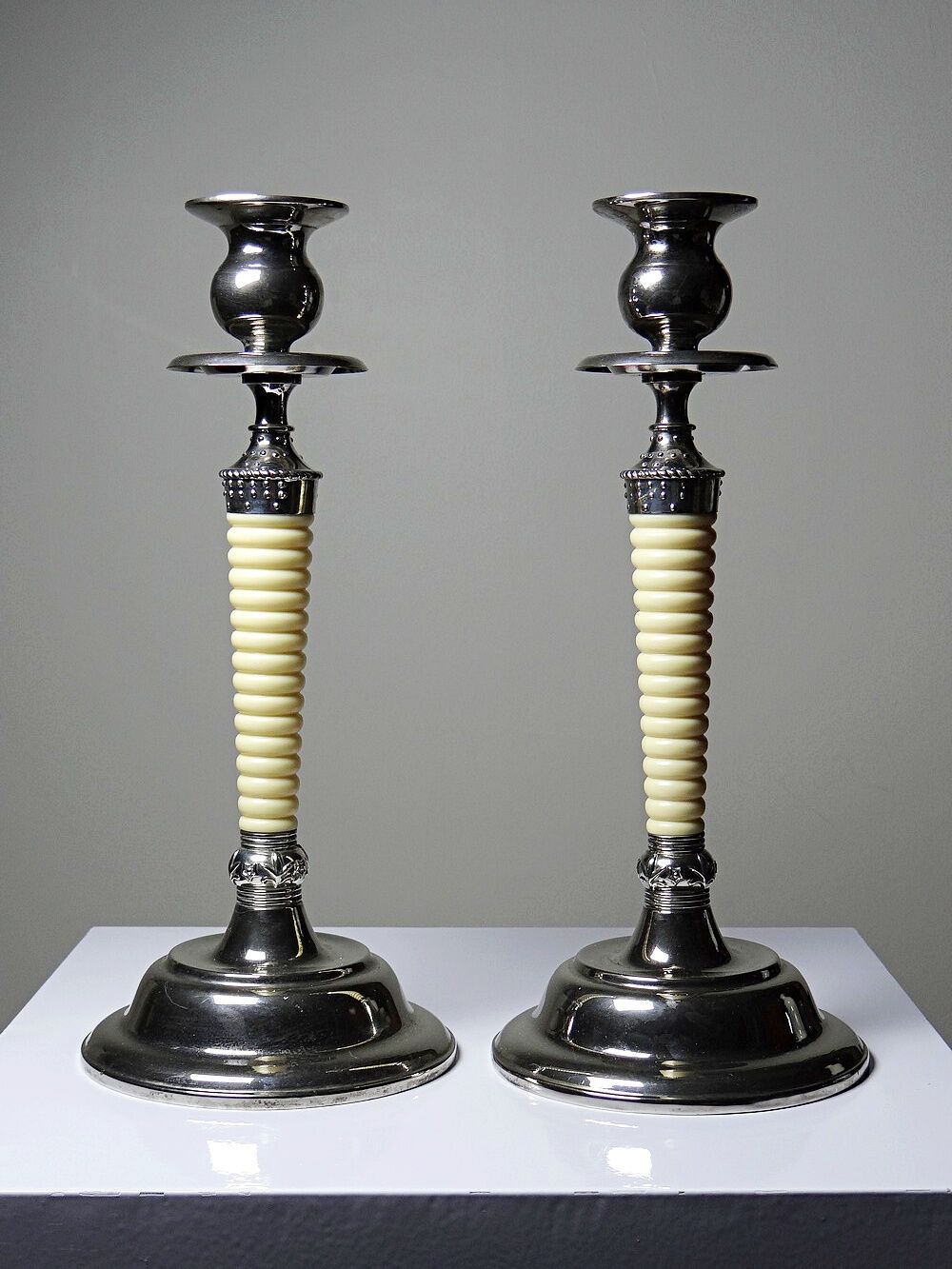 Pair of vintage candlestick holders in silver-plated metal with ivory-style plastic.