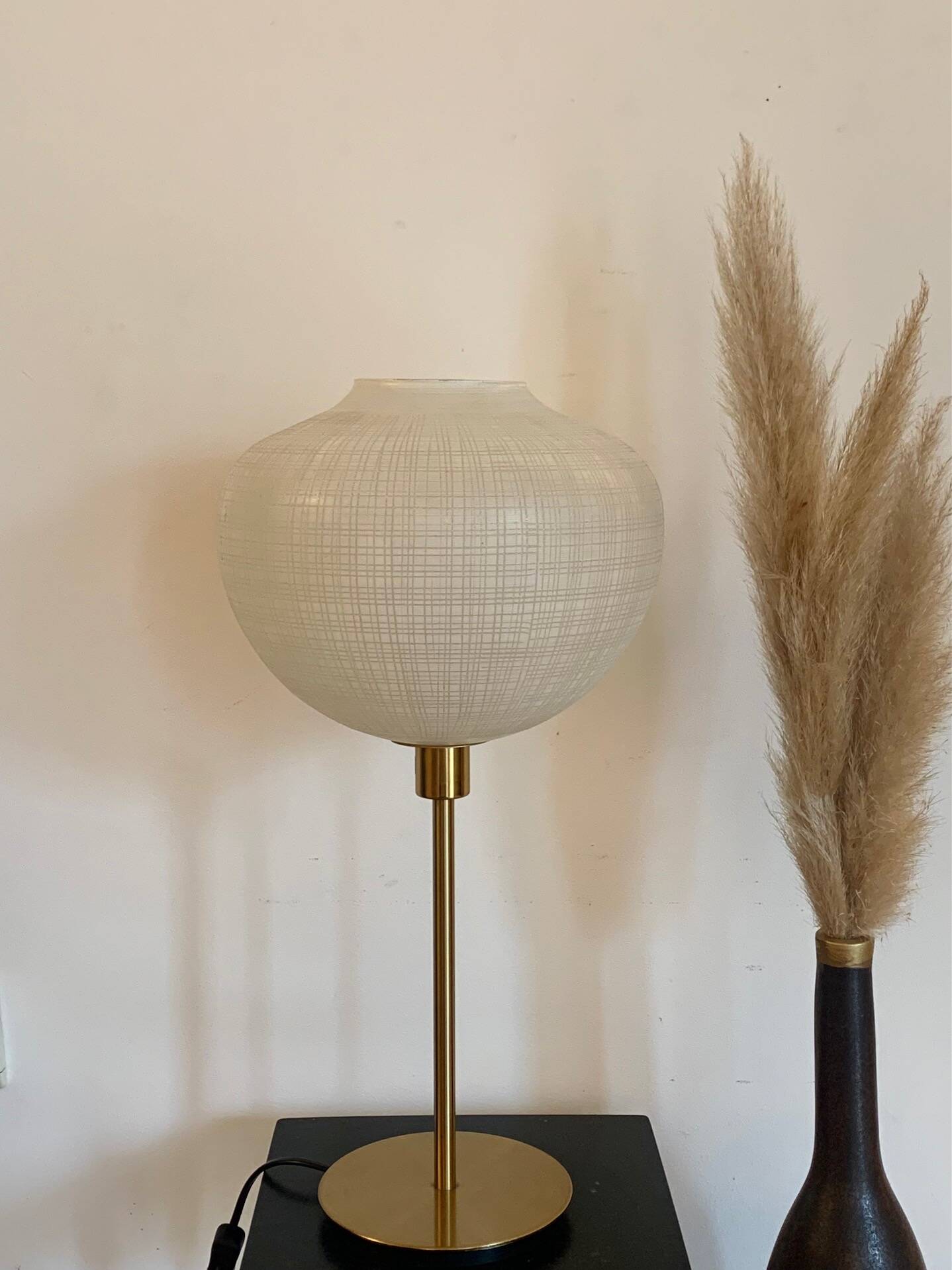 Table lamp with a white striped glass globe lampshade and a gold base