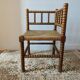 Antique corner chair by the fire with turned wood and straw seat.