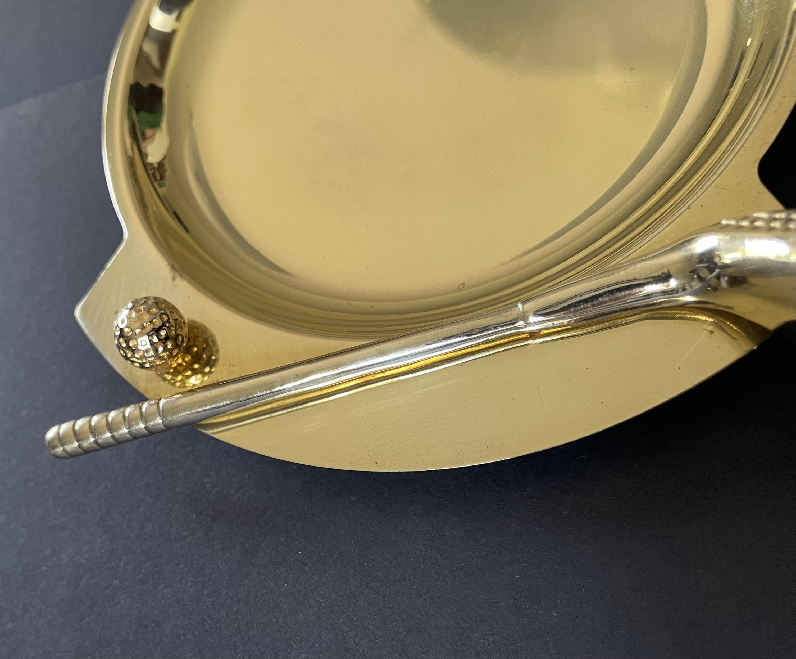 Round brass pocket tray with club and golf ball decoration.