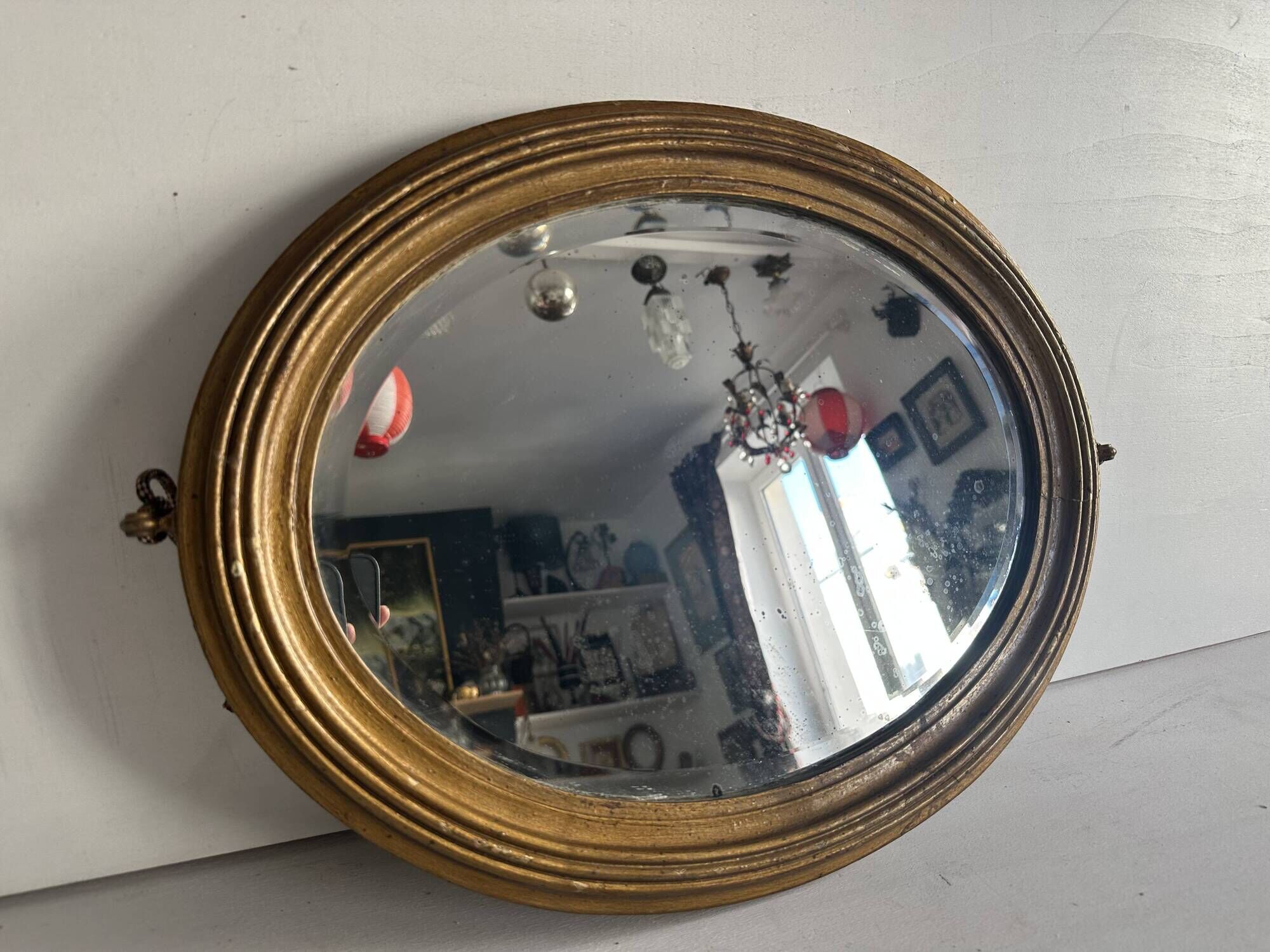 Antique oval mirror in gilded wood, bevelled mercury glass, 19th century.