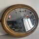 Antique oval mirror in gilded wood, bevelled mercury glass, 19th century.