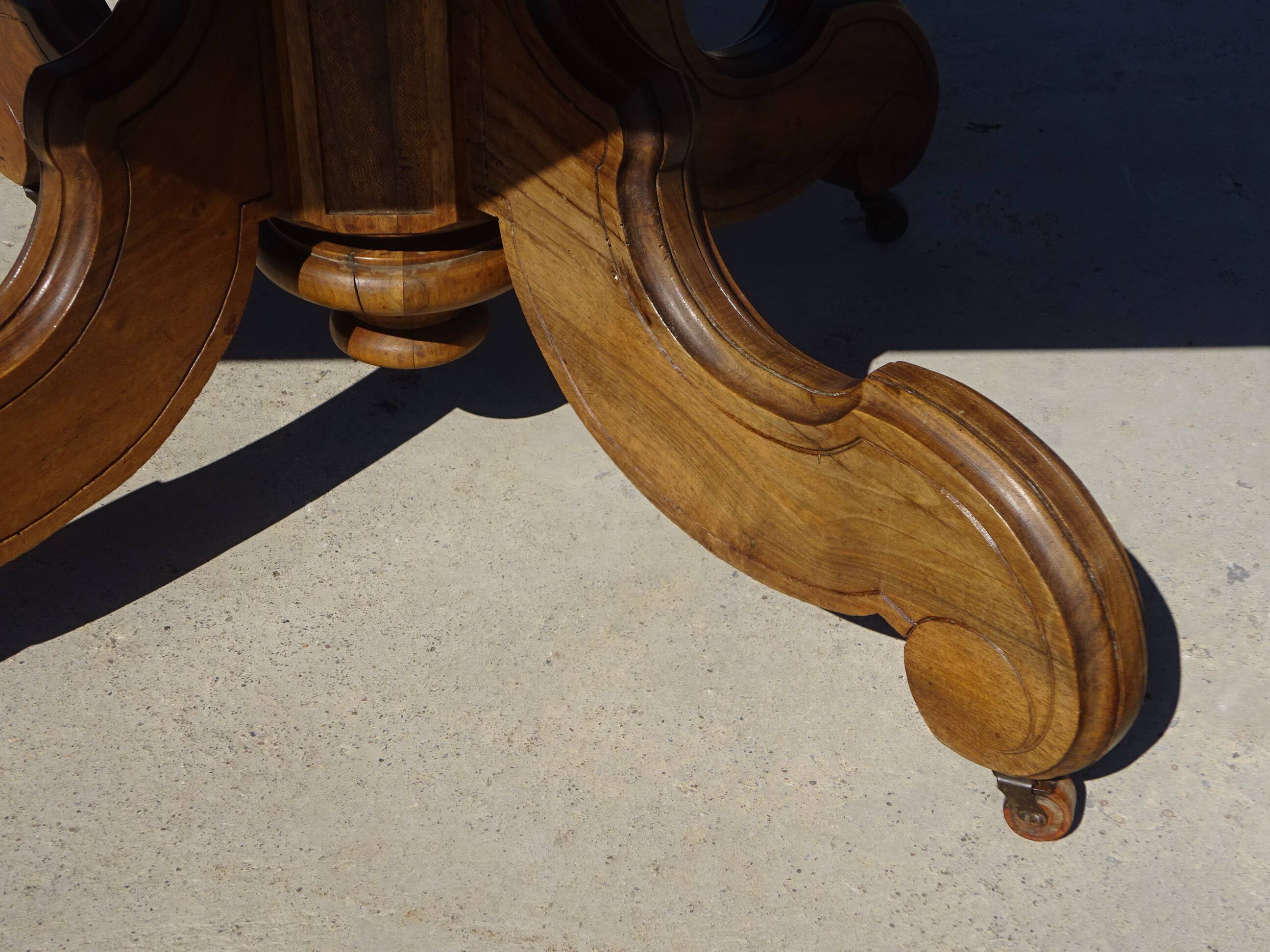 Old walnut table with a central leg.