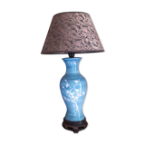 Large blue porcelain lamp with white flowers (cherry blossoms) on wooden stand.