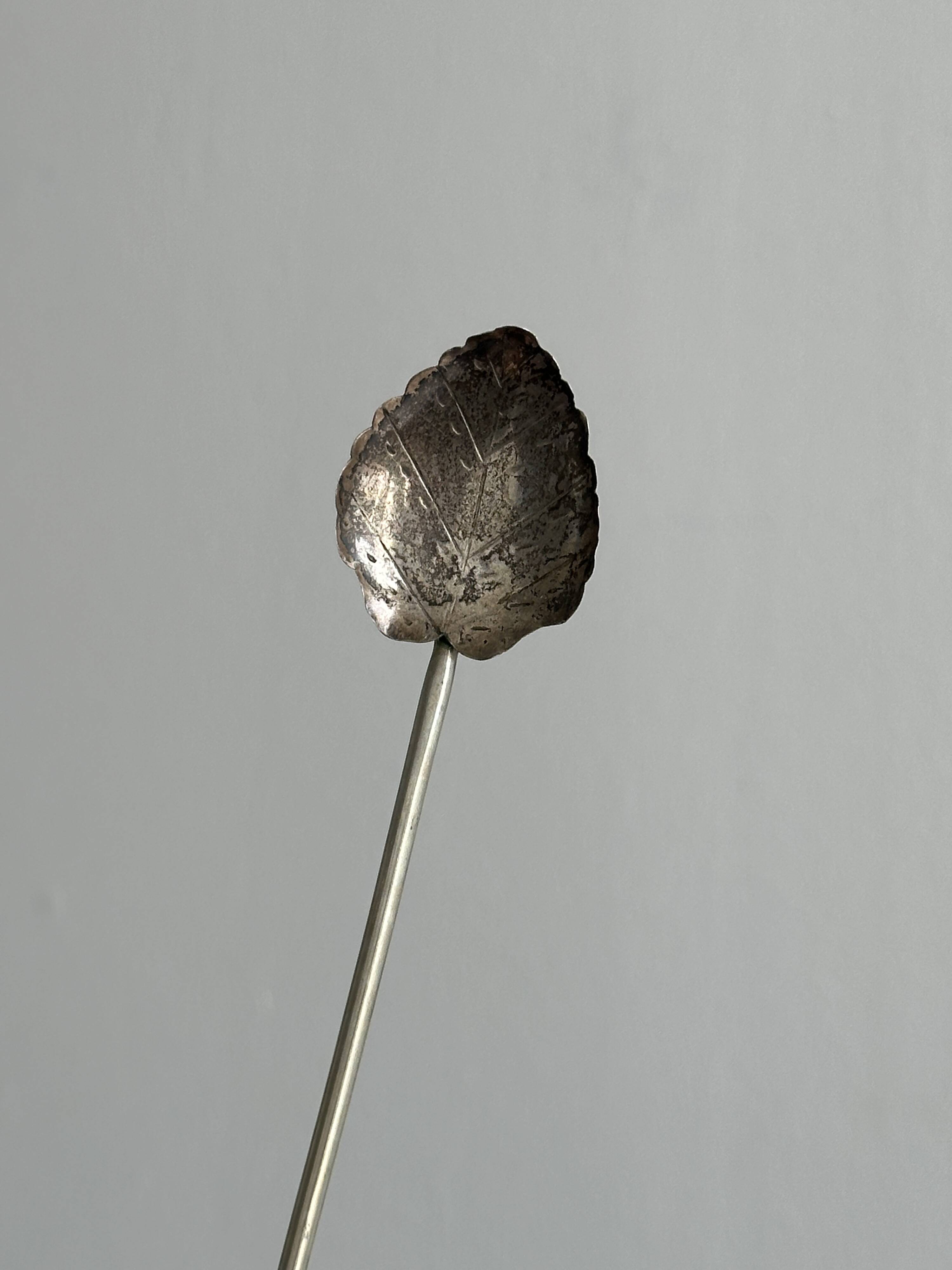 Vintage spoon in old metal, leaf pattern
