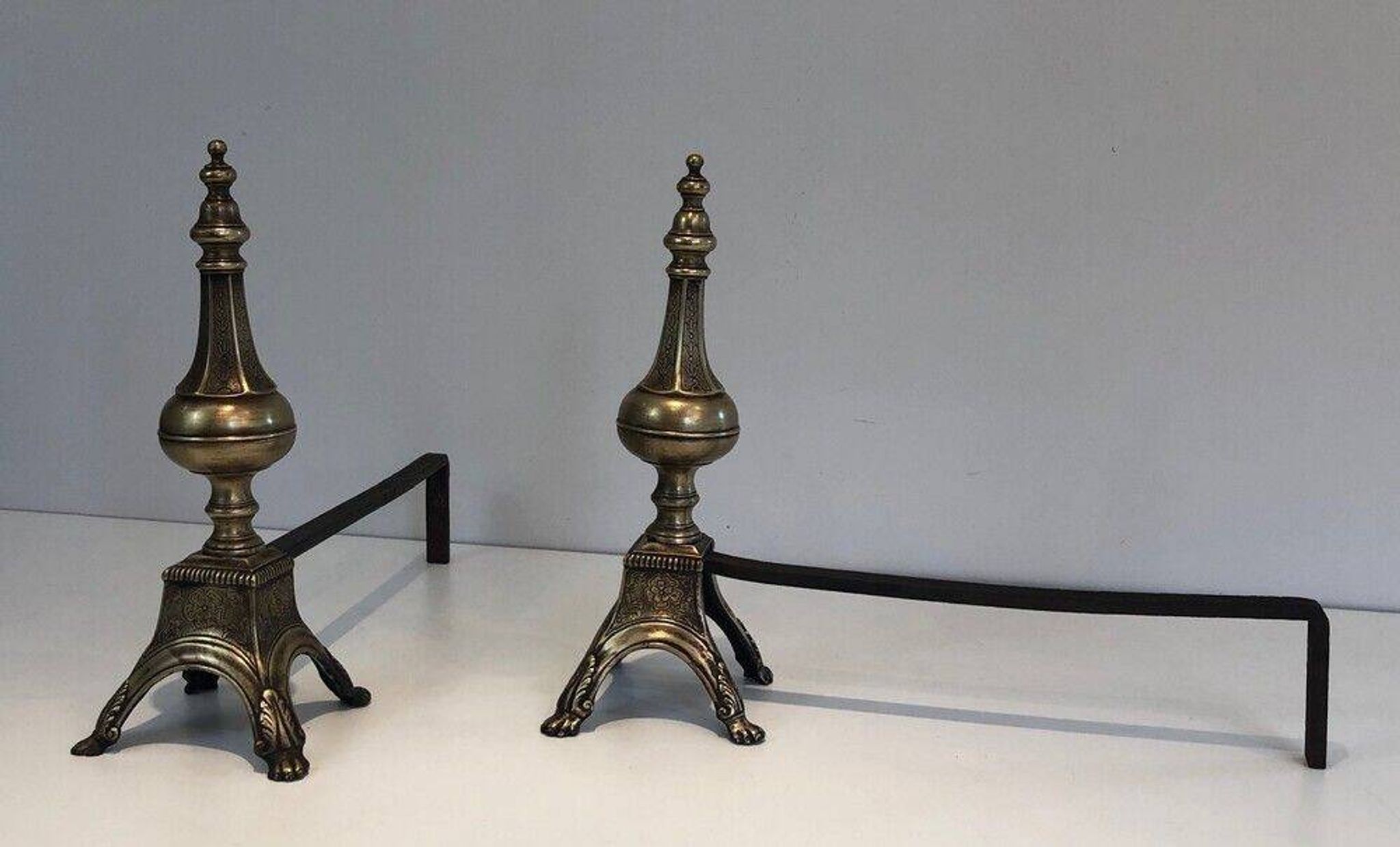 Pair of chiselled bronze and wrought iron fire dogs in the Louis XVI style.