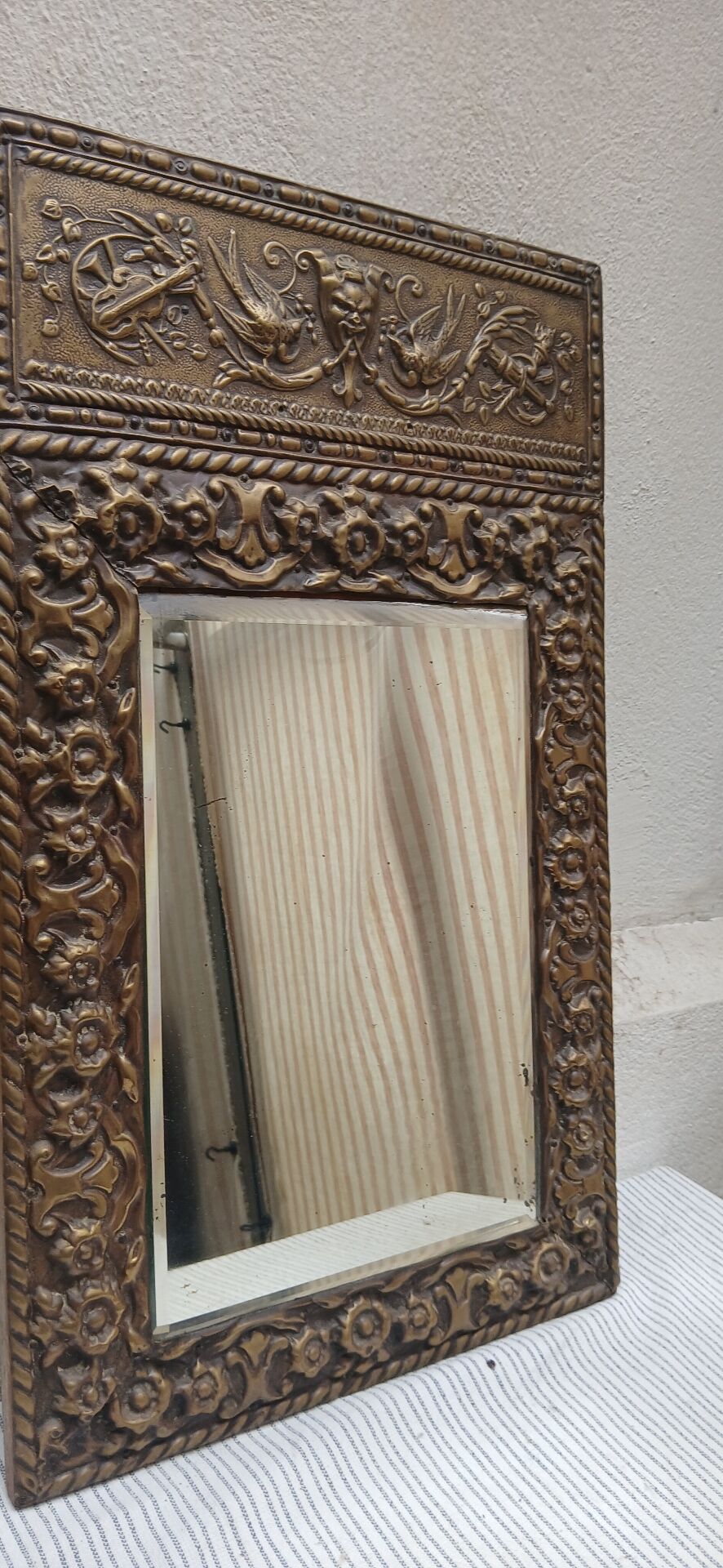 Bevelled mirror from the 1930s in repoussé brass.