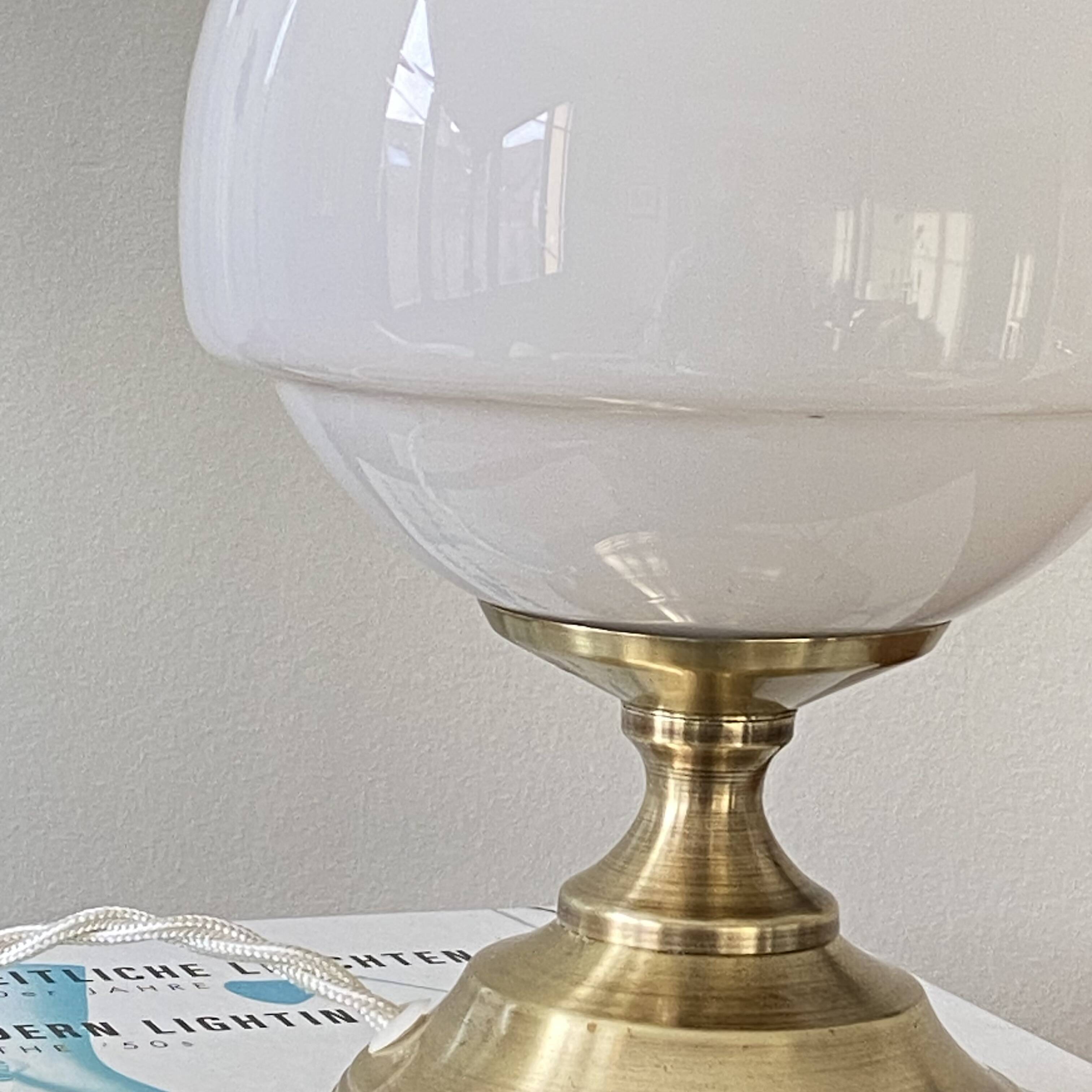 Antique white opaline glass globe table lamp with a brass base.