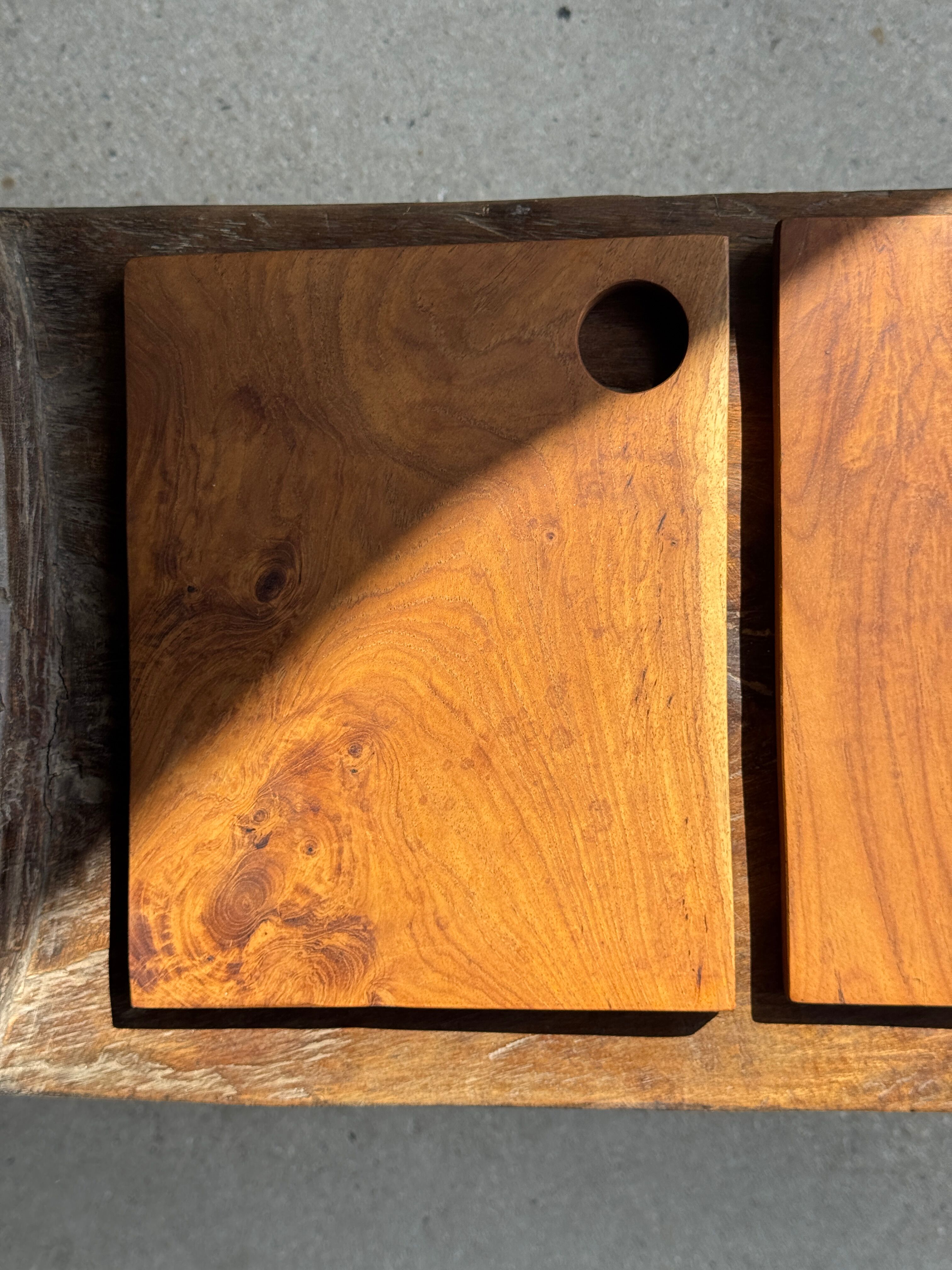Small rectangular teak monoxyle cutting board with a circular handle.