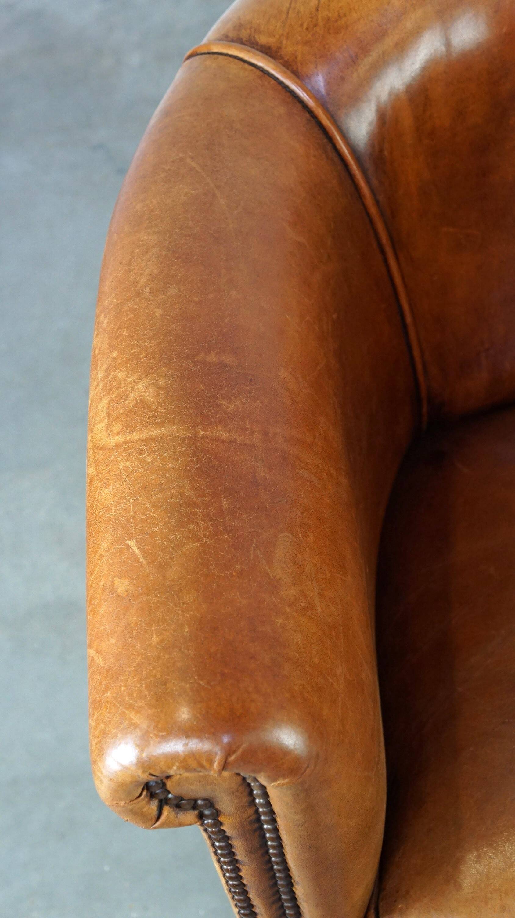 Neat and subtle sheepskin club chair, finished with decorative studs and a fixed seat cushion