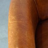 Neat and subtle sheepskin club chair, finished with decorative studs and a fixed seat cushion