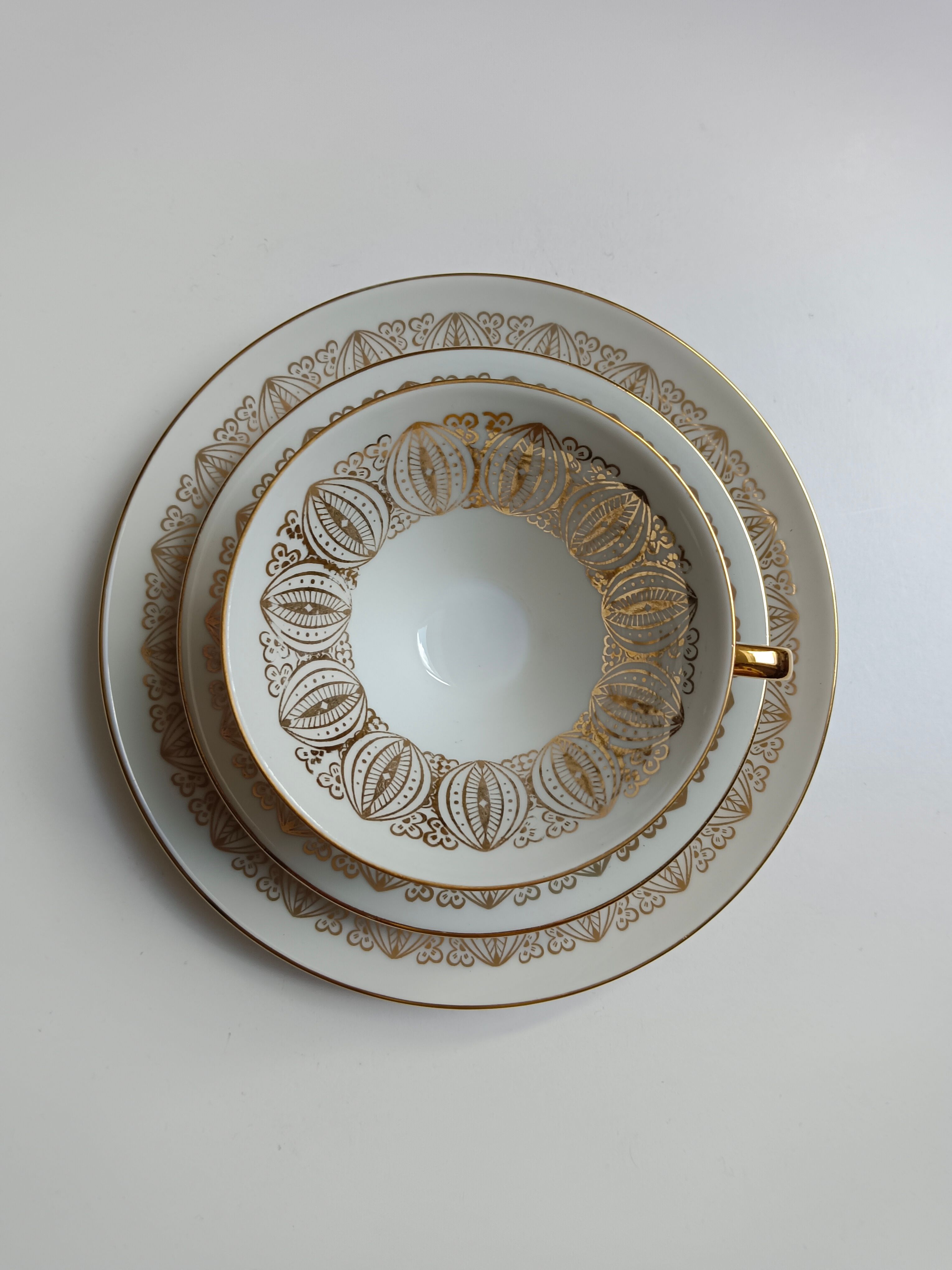 Solitaire tea cup, saucer, and dessert plate in white and gold.