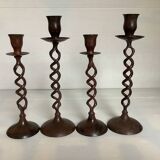 Four twisted metal candle holders with a rusty appearance