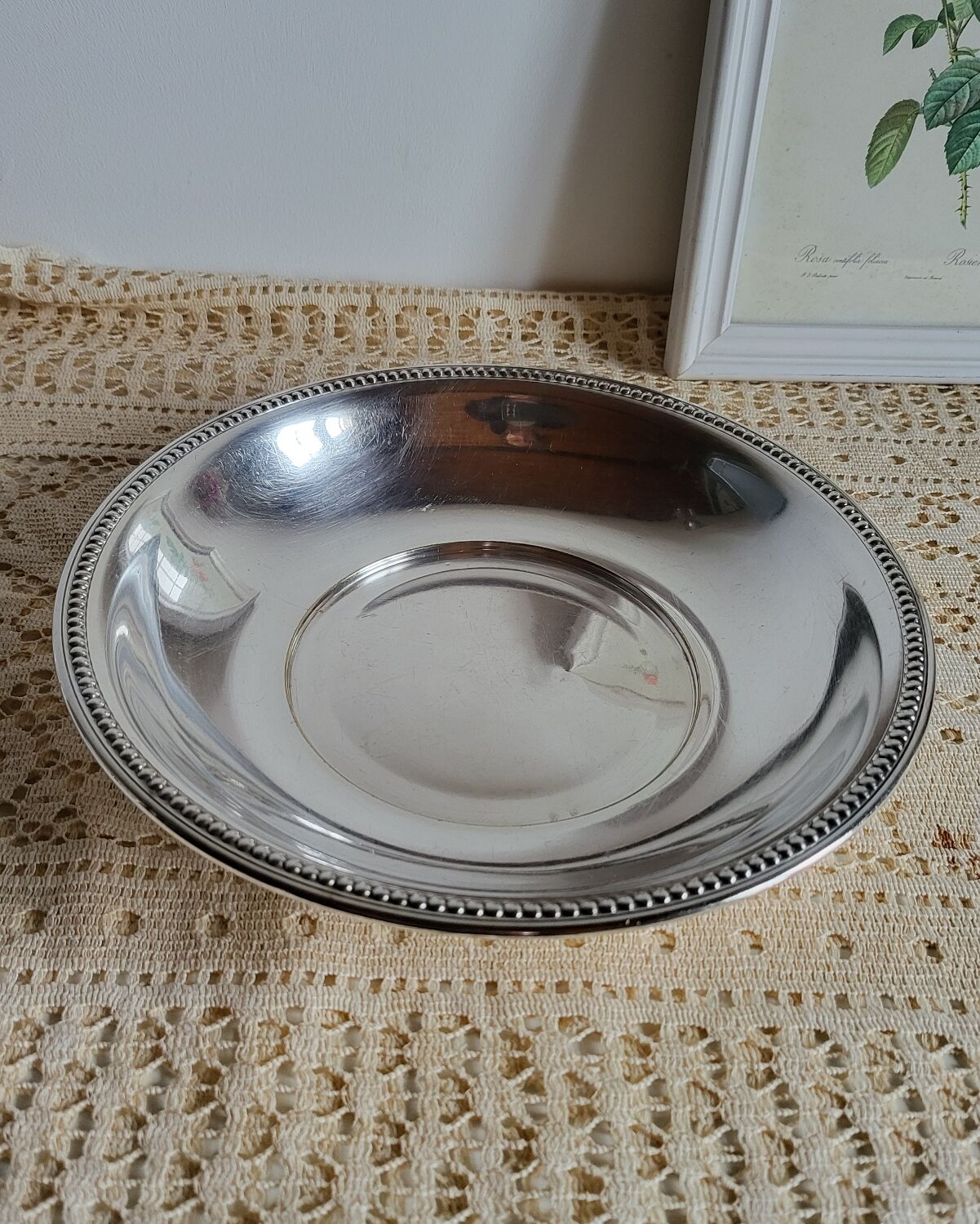 Shallow round metal plate with pearl bead decoration.