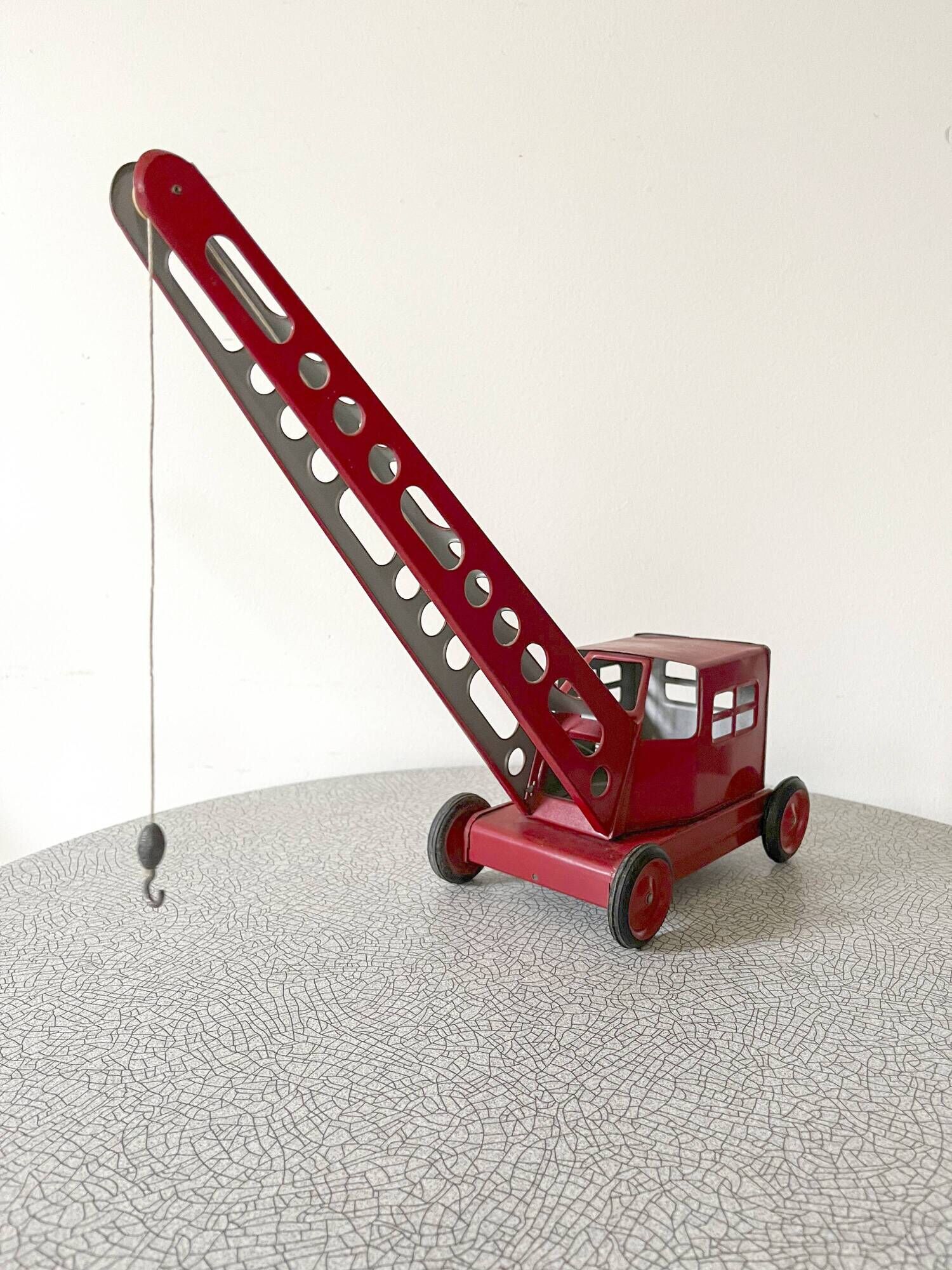 Grue de chantier rouge en tôle datant des années 60 avec mécanisme manuel