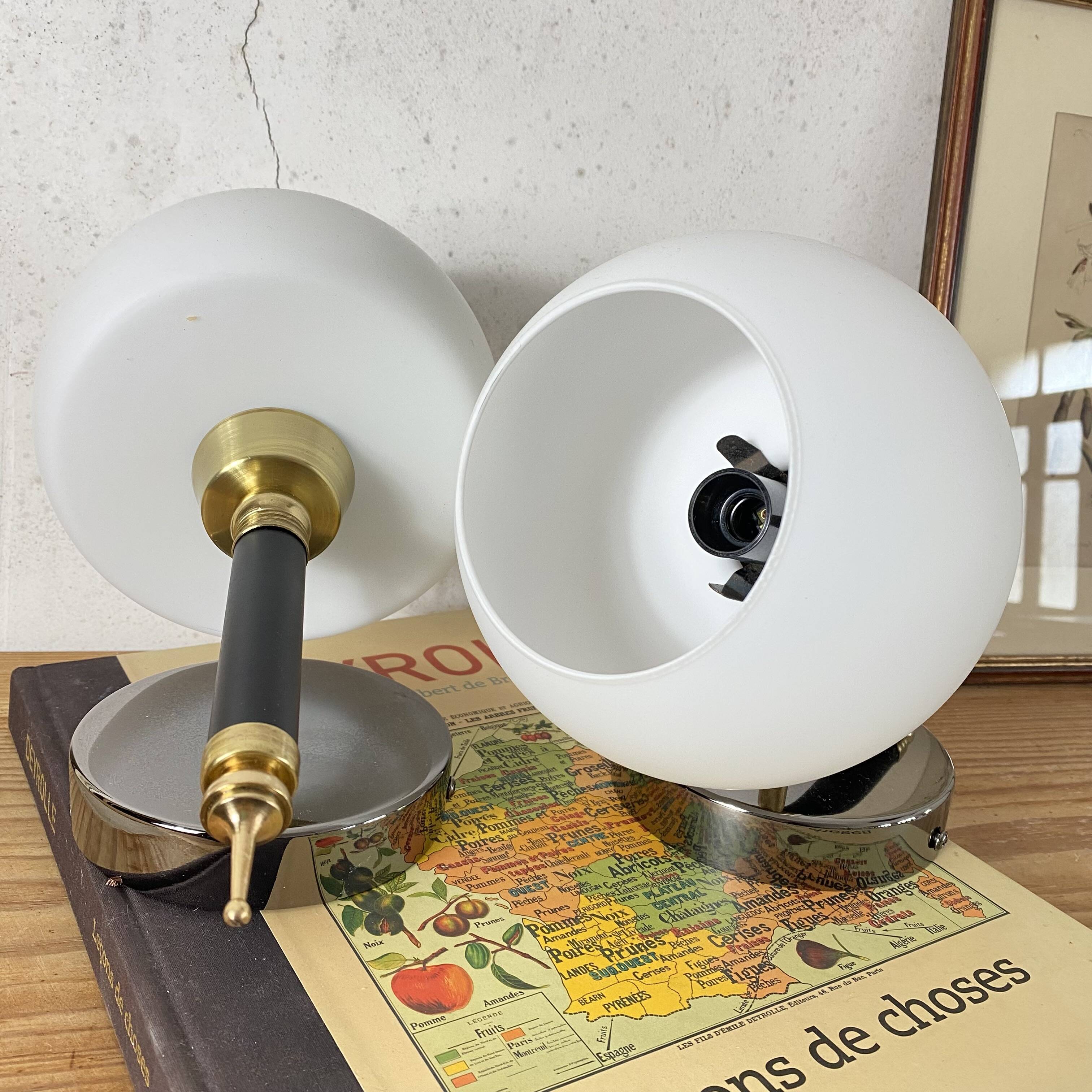 Pair of wall sconces with brass torch and white glass globe.