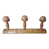 Wall-mounted wooden coat rack in bamboo style with 3 mushroom-shaped hooks.