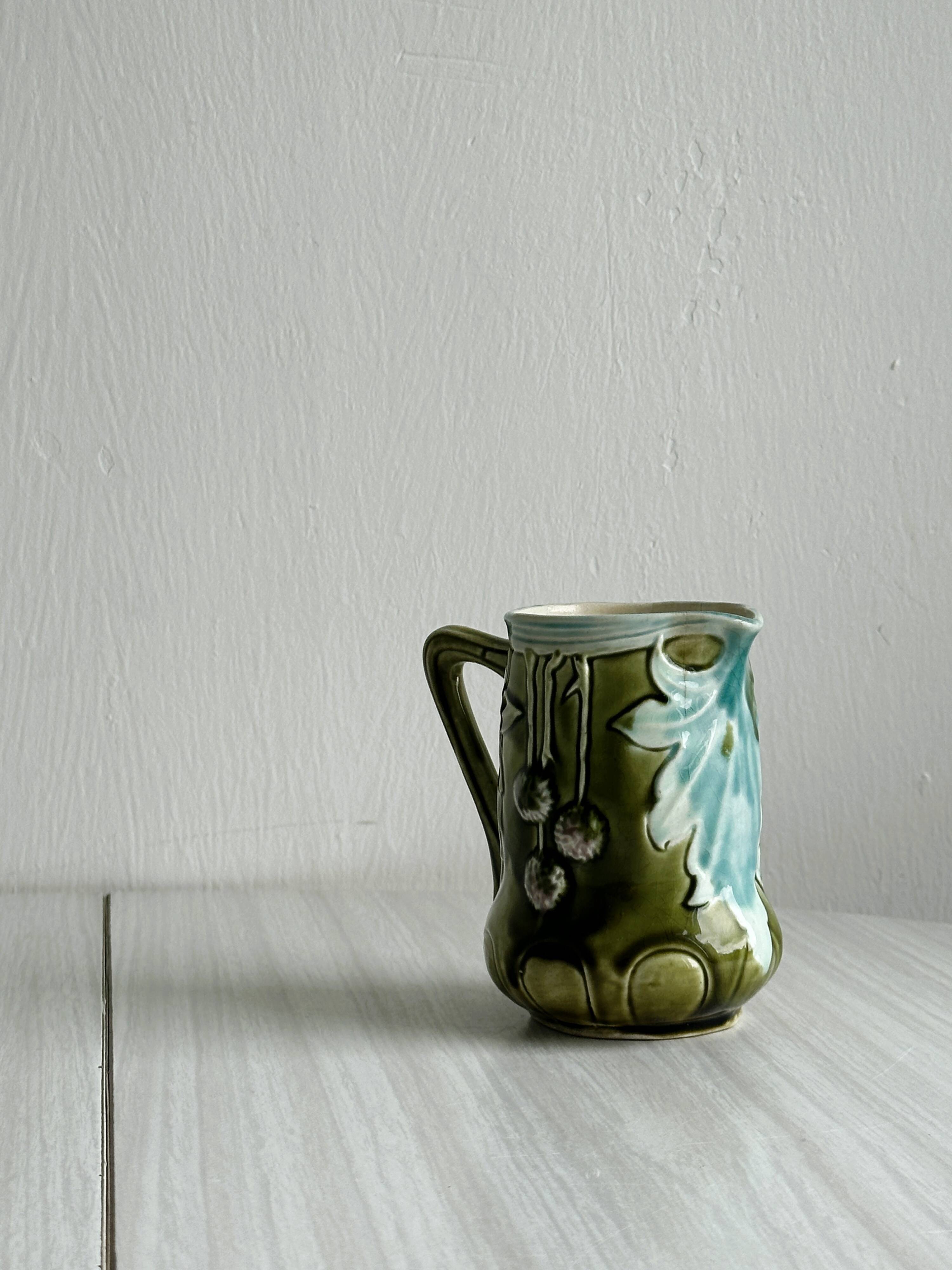 Green slip milk jug with floral patterns.
