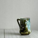 Green slip milk jug with floral patterns.