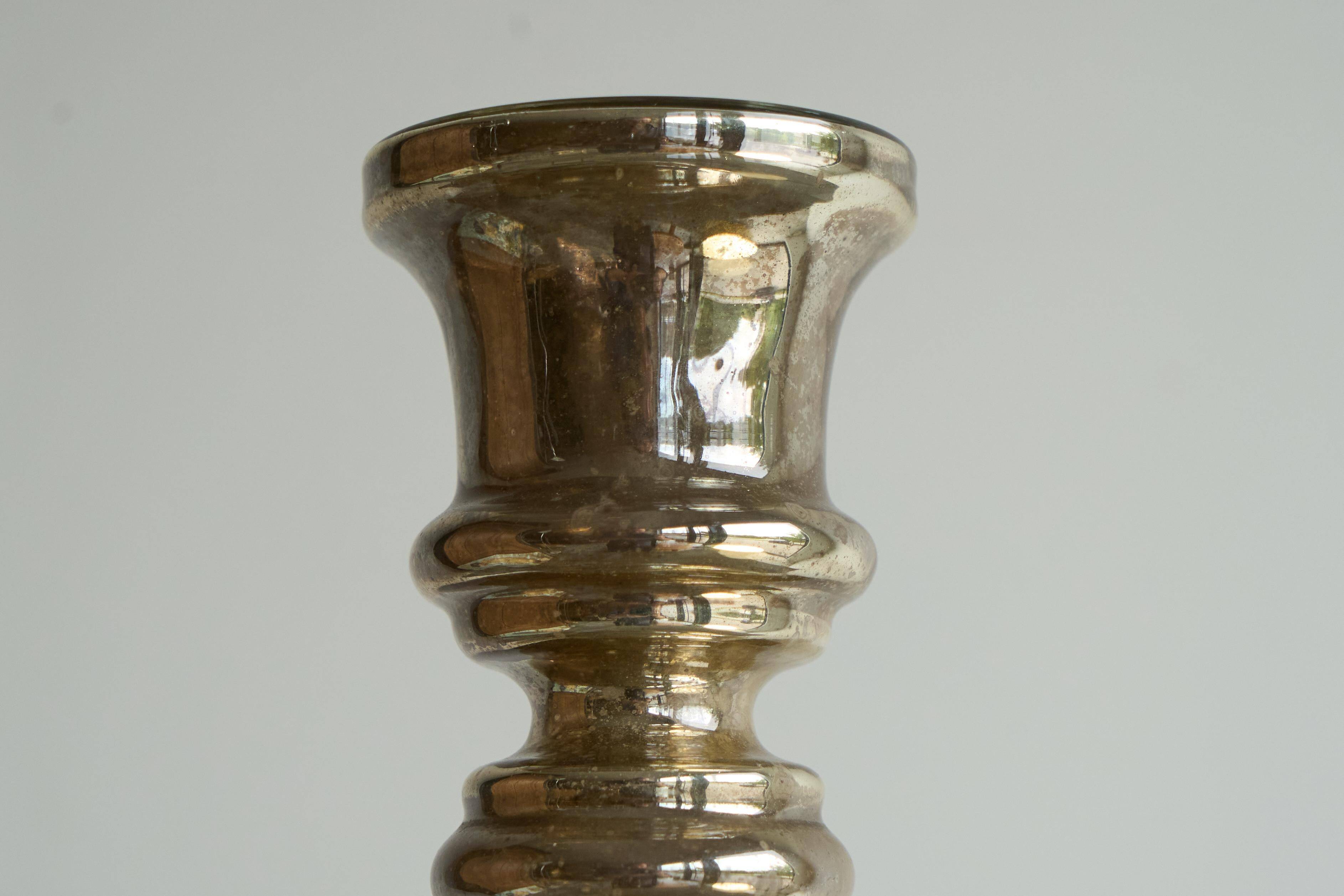 Antique mercury glass candlestick with a patina and silver finish.