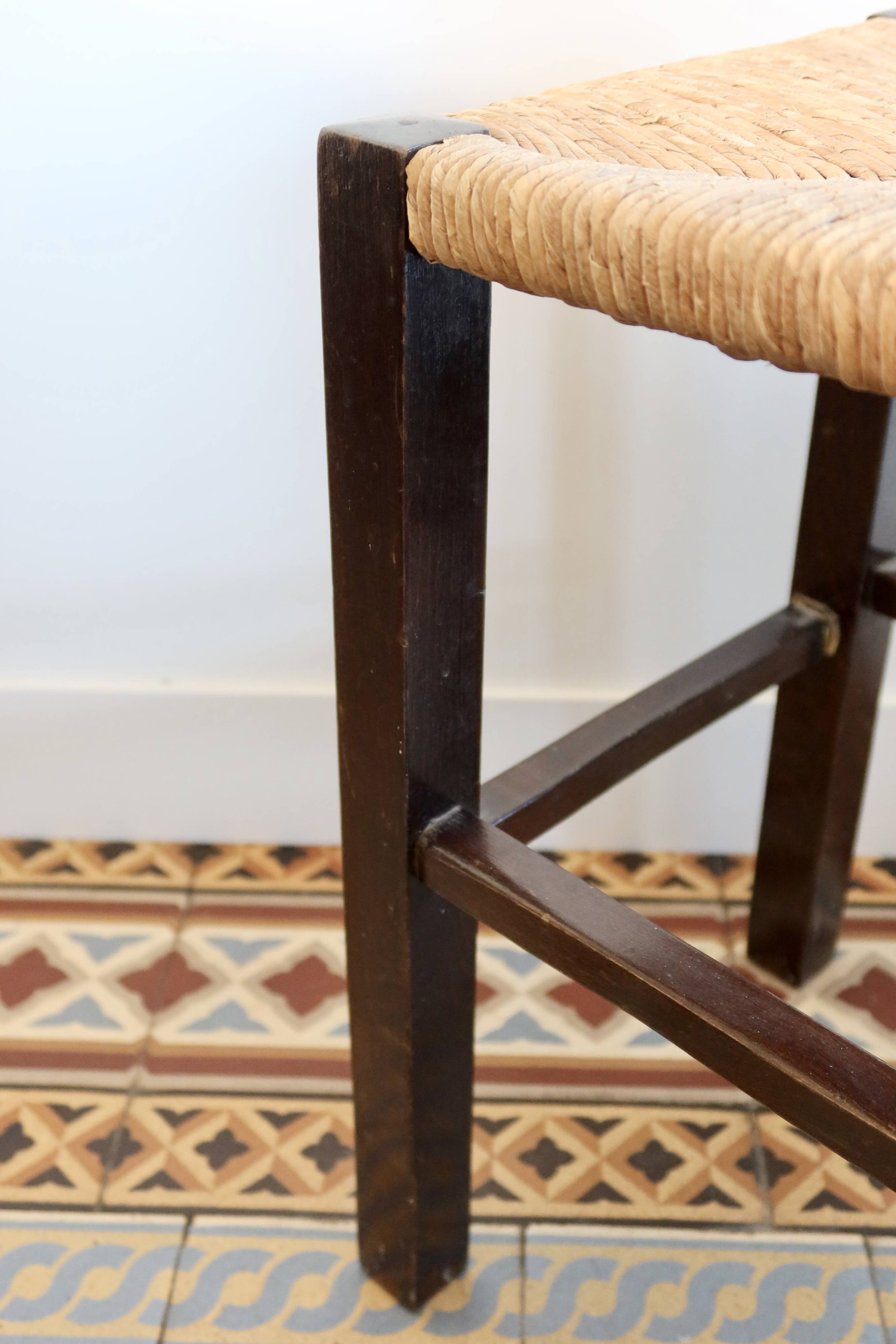Vintage rustic stool in wood with a straw seat.