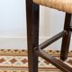 Vintage rustic stool in wood with a straw seat.