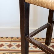 Vintage rustic stool in wood with a straw seat.
