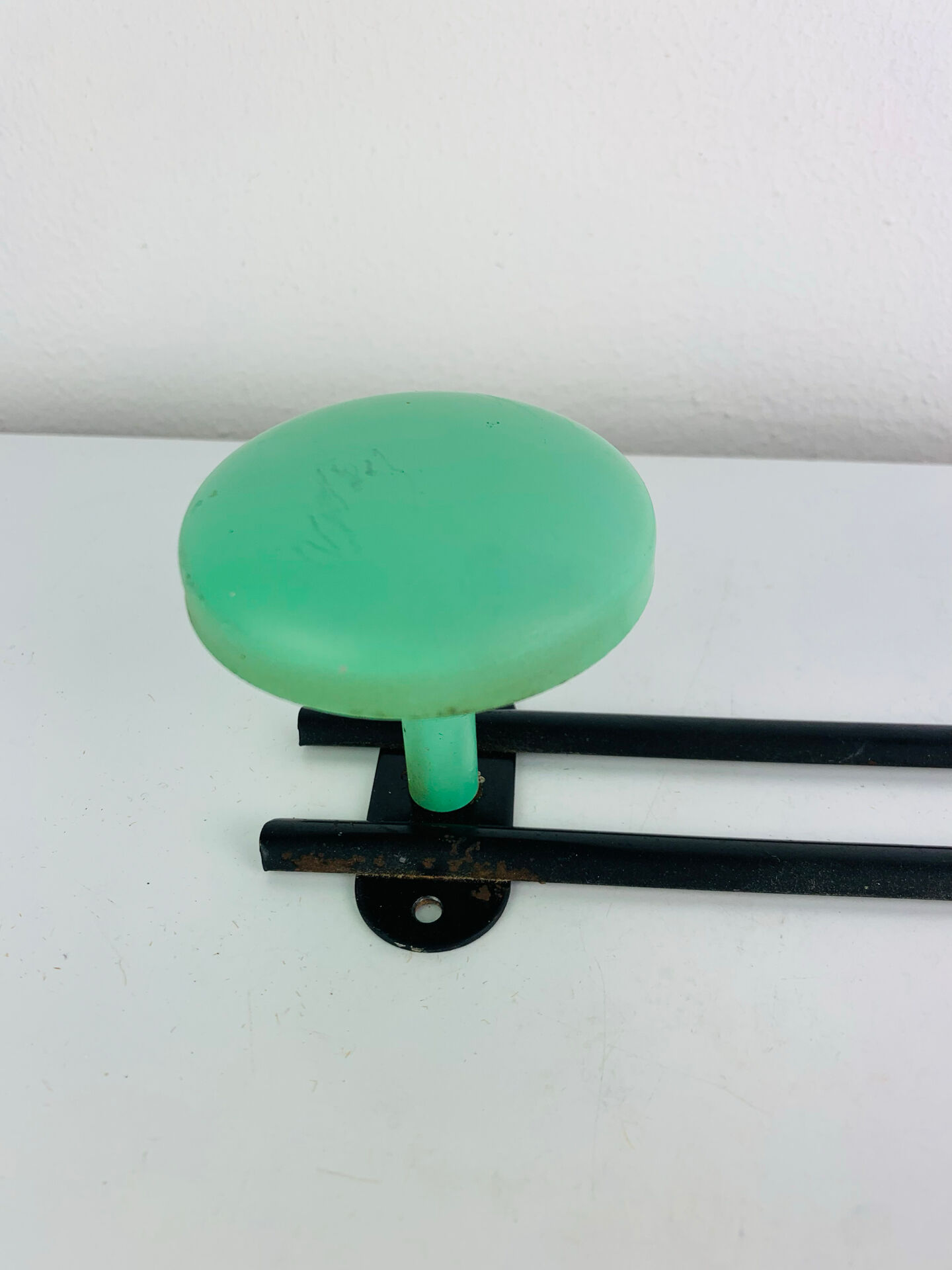 Wall-mounted coat rack with 2 green hooks from the 1950s.