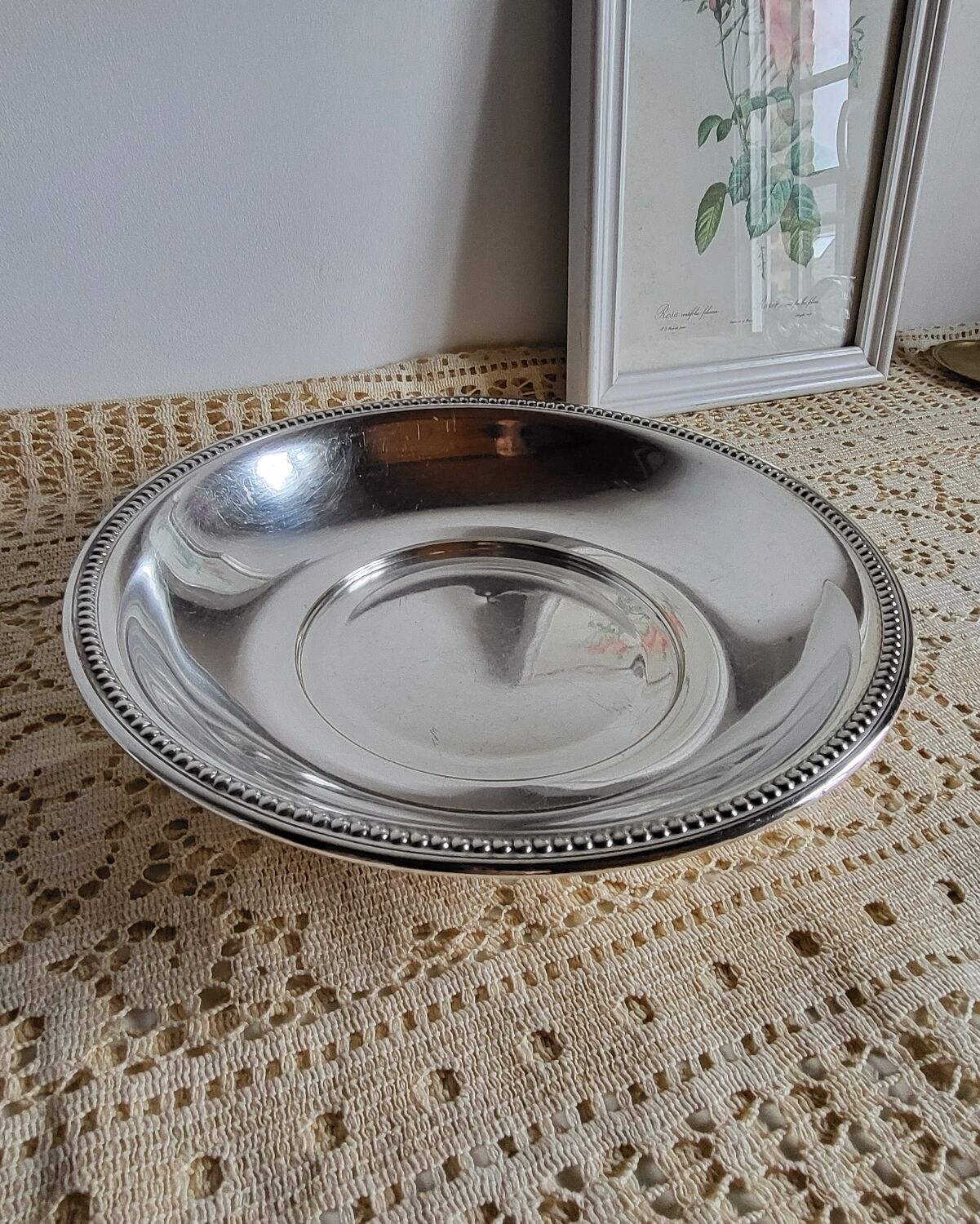 Shallow round metal plate with pearl bead decoration.
