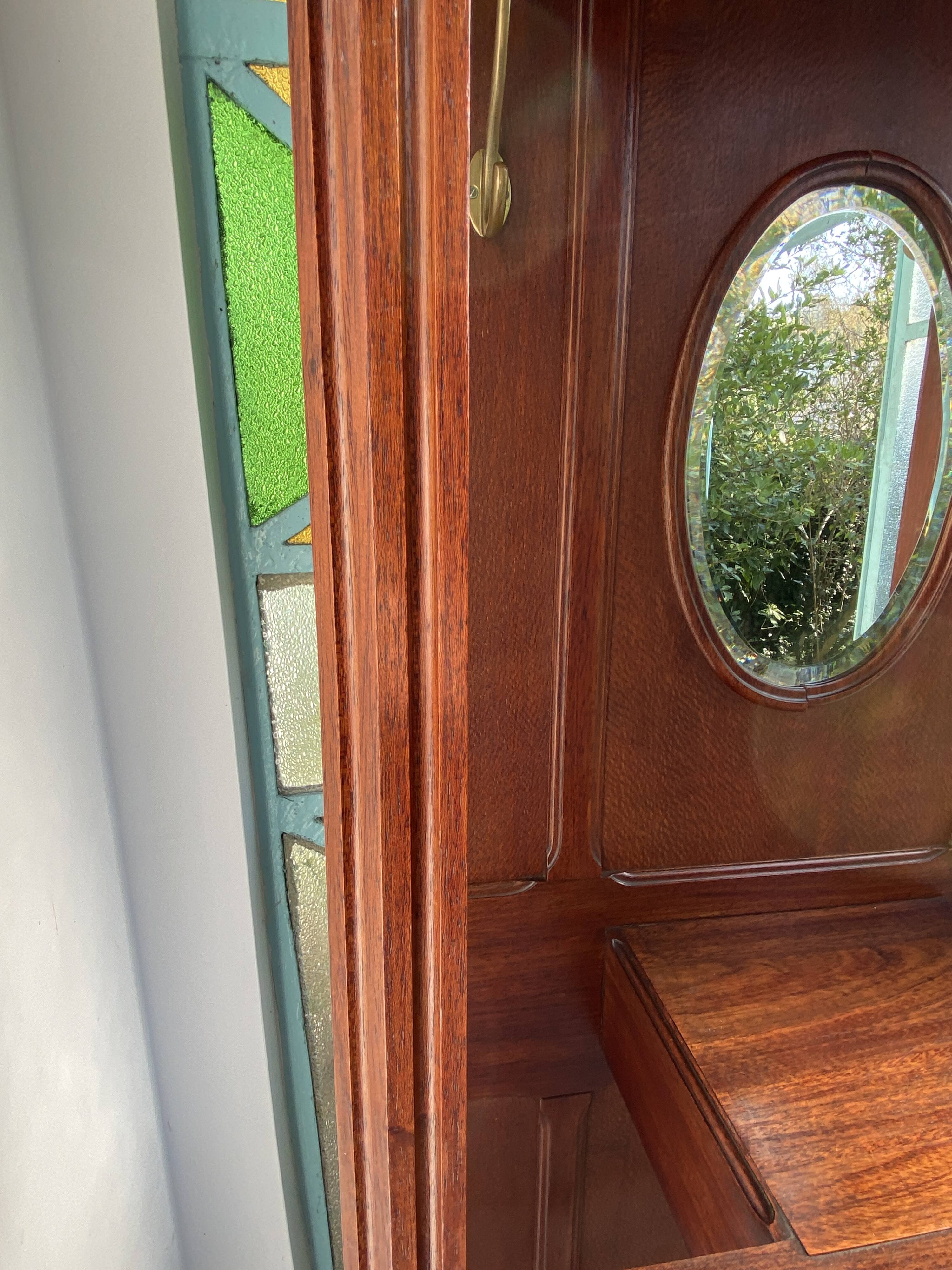 Antique wooden coat rack with mirror and shelf.