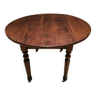 Old round table with folding shutters on casters in solid wood in very good condition