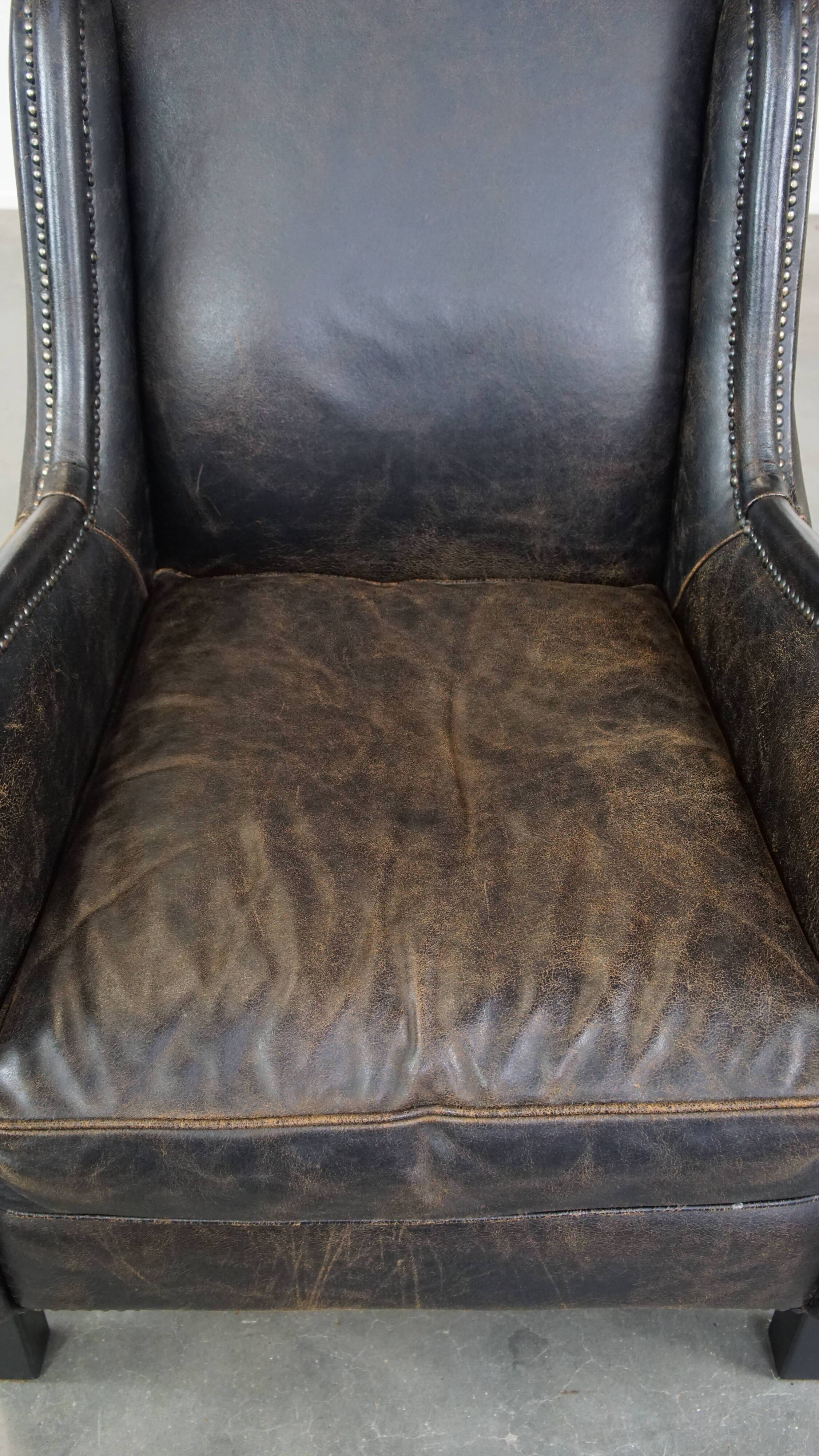Black cow leather armchair in industrial style finished with decorative nails