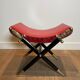 Neoclassical curule stool in red leather, decorated with crossed swords in bronze and metal covered in black leather.