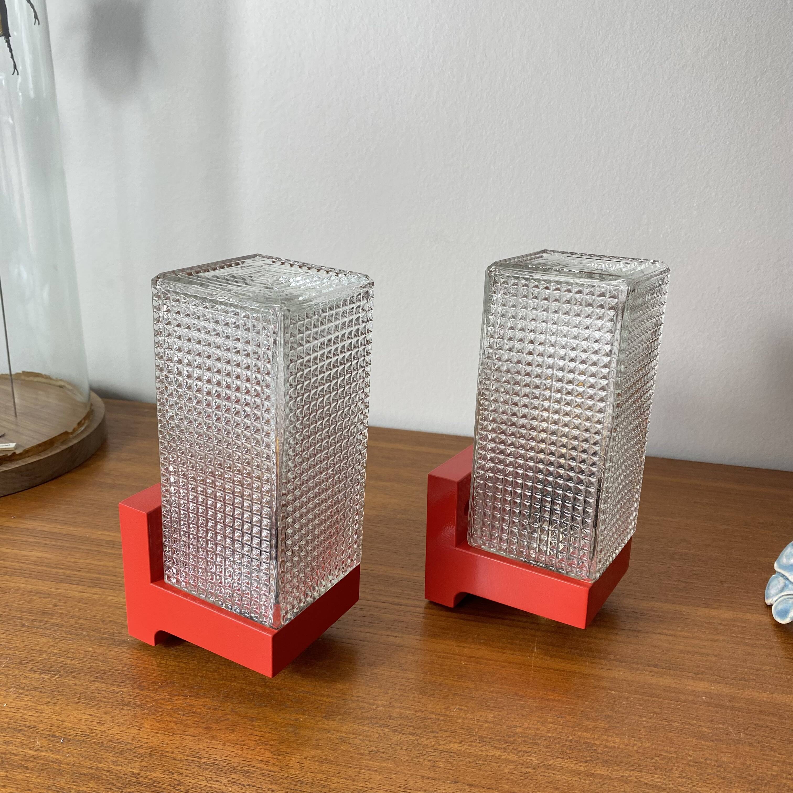 Pair of vintage wall lights in red plastic and clear glass.