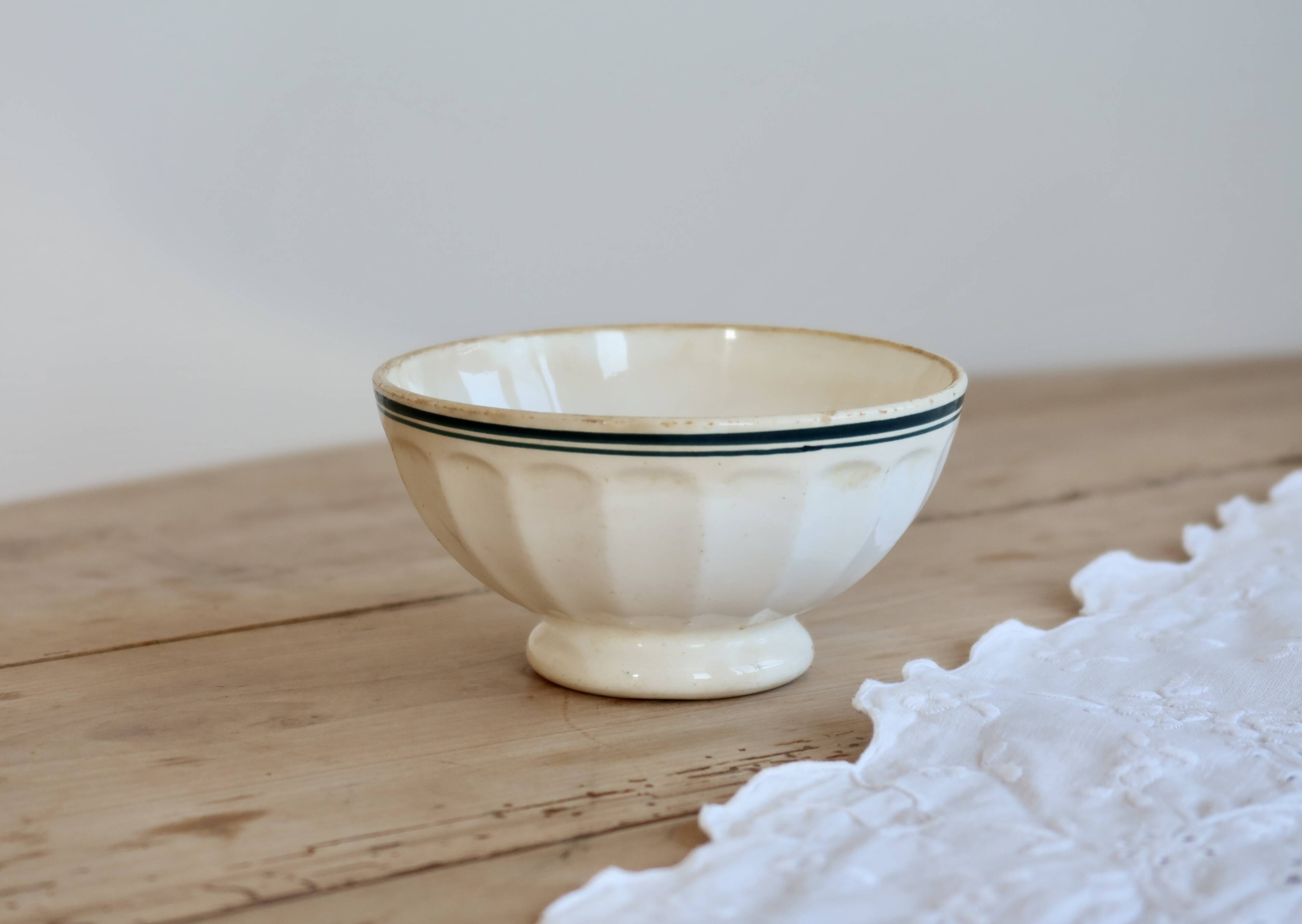 Old ivory ceramic bowl with double green trim.