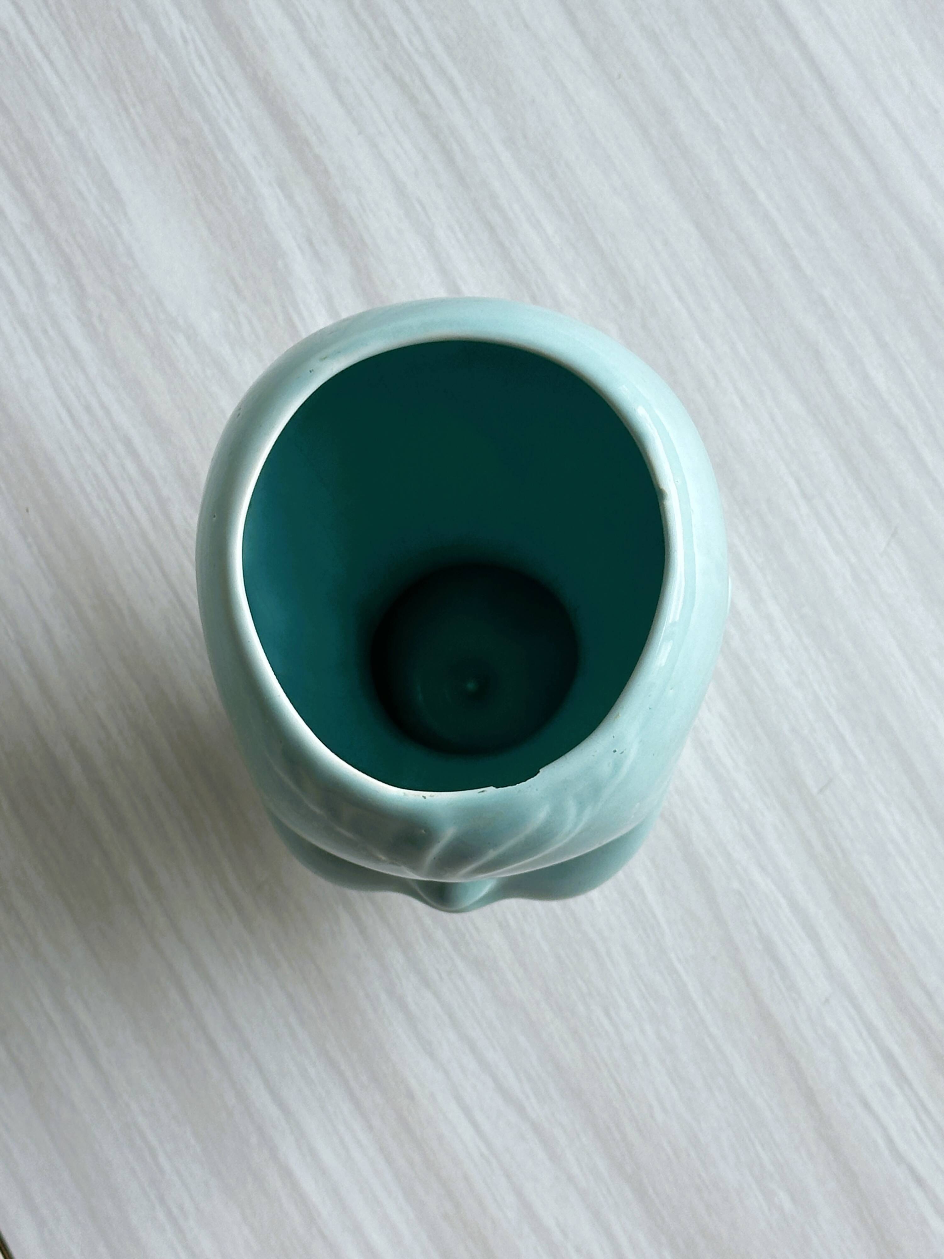 Turquoise plant pot in the shape of a vintage doll's head.