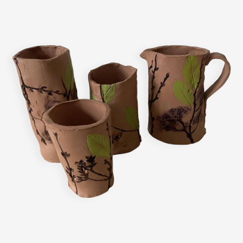 Artisanal pottery set in red clay with harmonious plant motifs