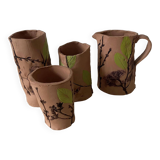 Artisanal pottery set in red clay with harmonious plant motifs
